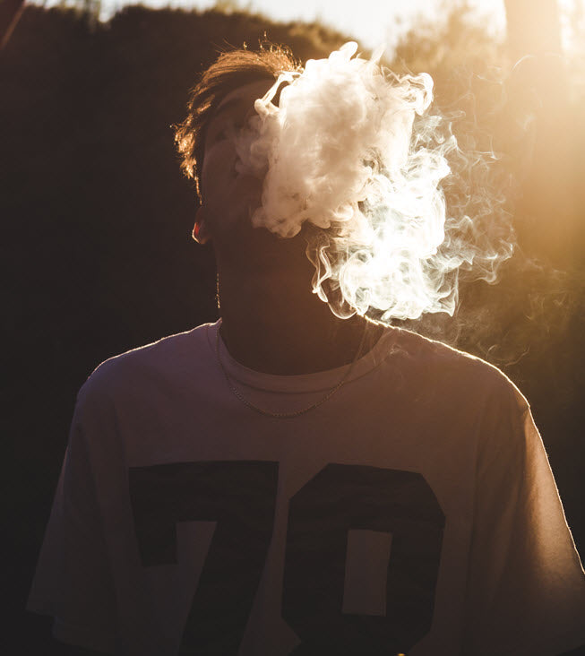 Young man blowing smoke in to the air. Photo by Dani Ramos on Unsplash