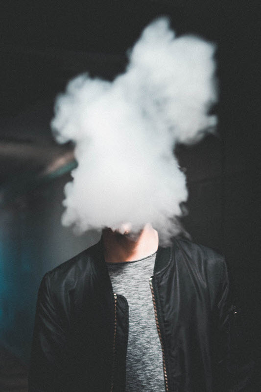 Photo by Luther Bottrill on Unsplash - Man vaping with cloud of smoke disguising face